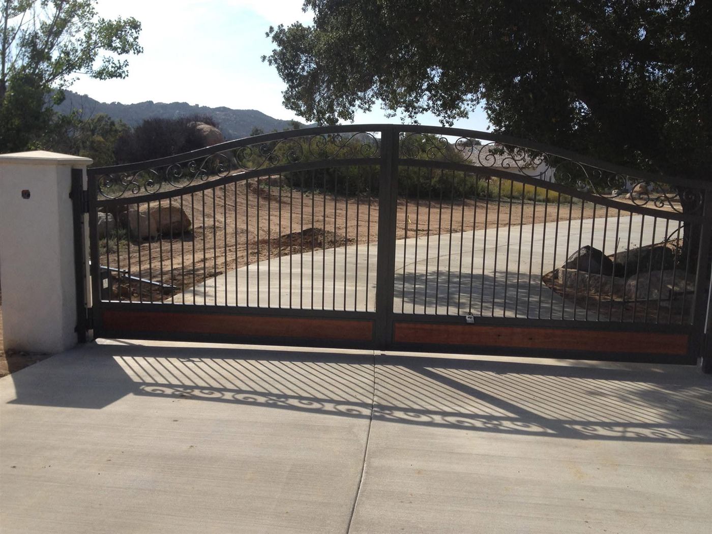 Arched wrought iron driveway gate with wood accents